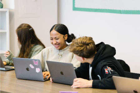 Two students collaborating on a laptop during hands-on project work